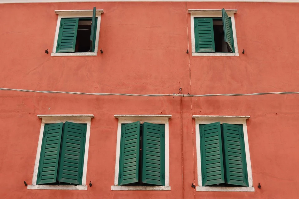 Façade enduite rouge brique aux volets verts